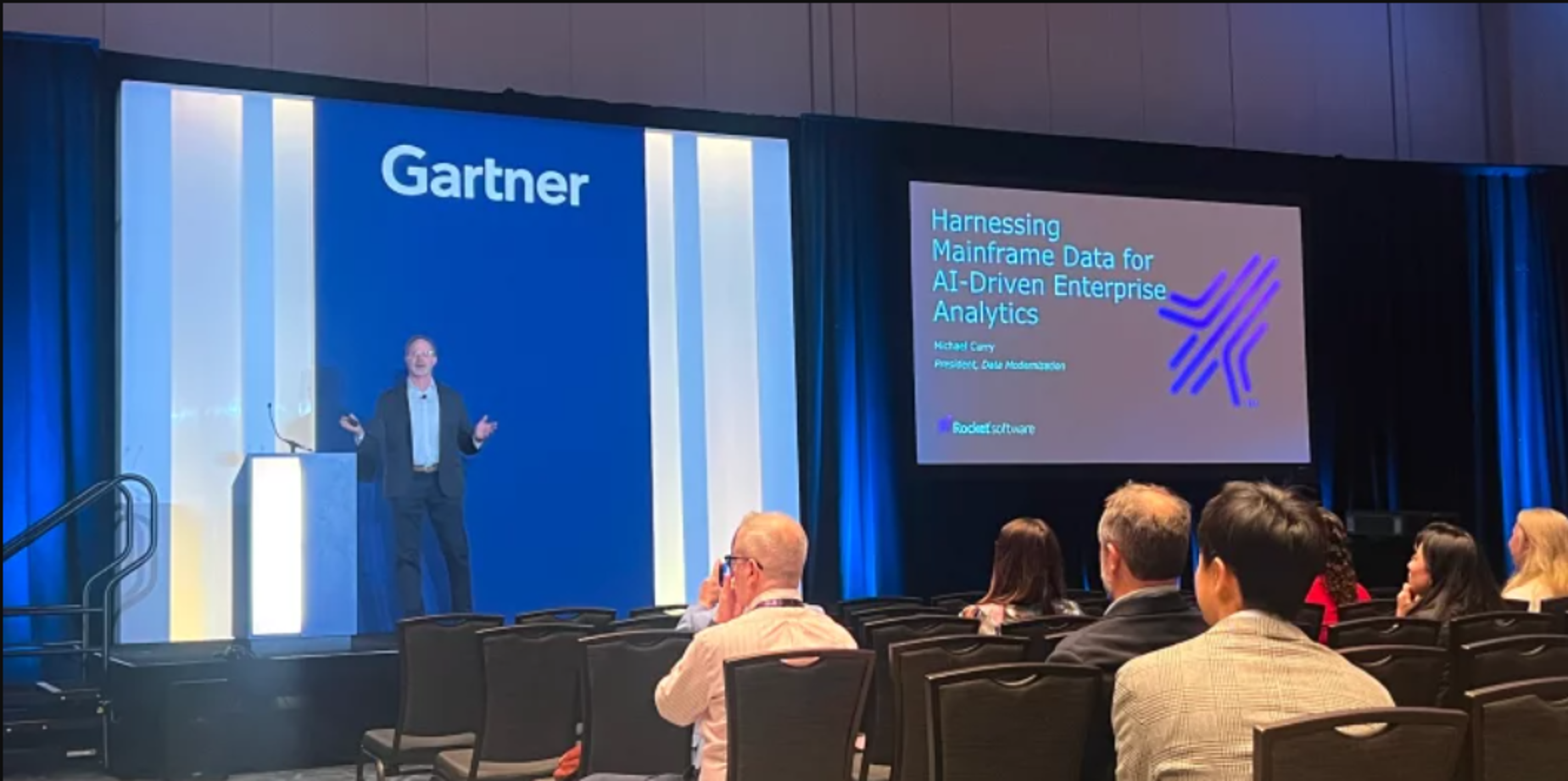 A man doing a presentation titled Harnessing Mainframe Data for AI-driven Enterprise Analytics